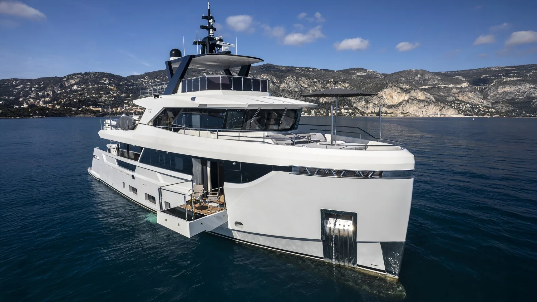 32 m motor yacht at anchor with the master-cabin balcony deployed from the starboard hull side